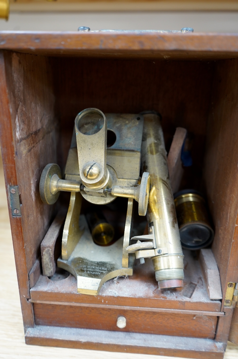 A mahogany cased late 19th century brass microscope by J.H. Steward, 456 West Strand London, with a drawer underneath containing a few prepared microscope slides, case 27cm high, 19.5cm wide, 15.5cm deep. Condition - poo